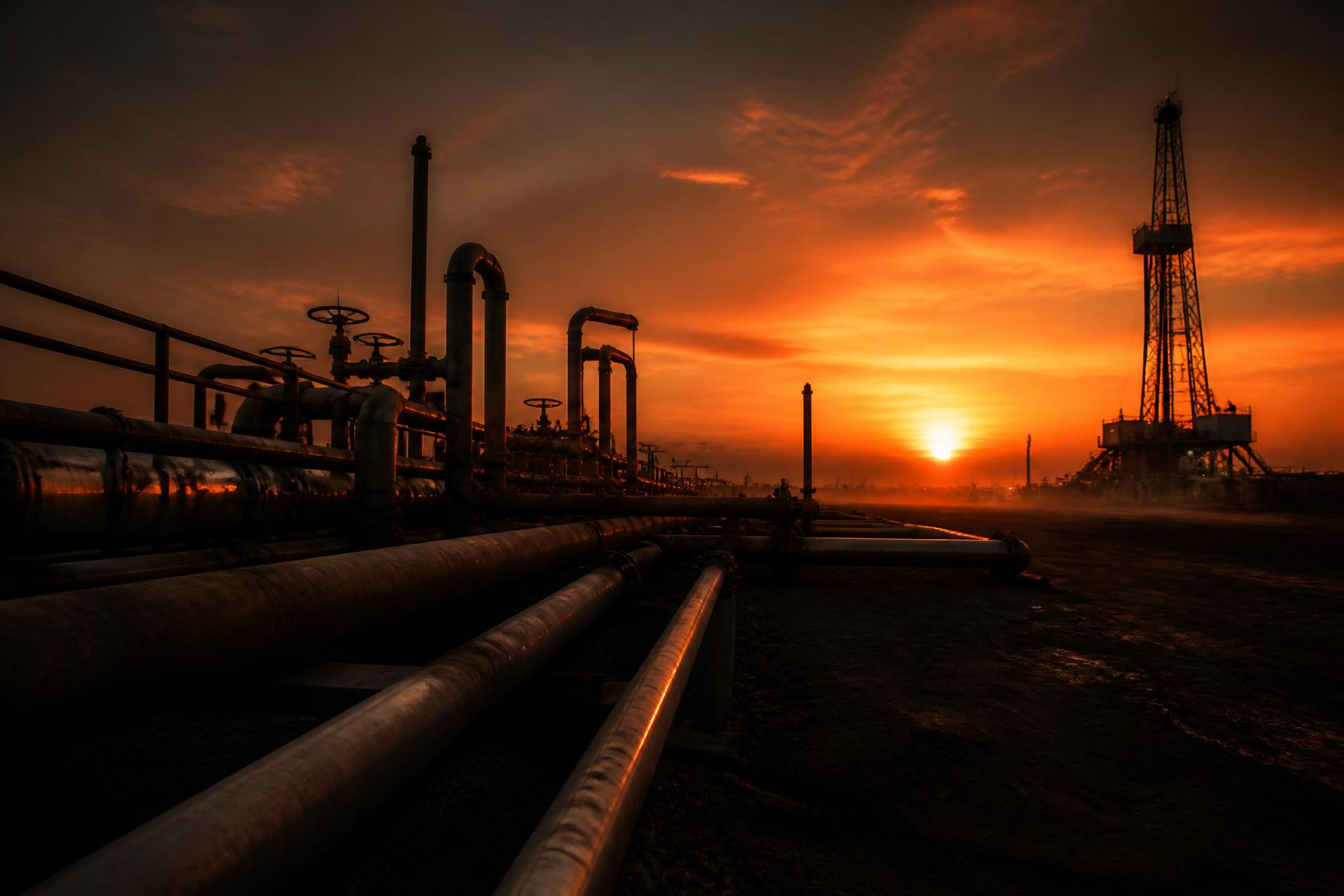 Pipeline infrastructure and a drilling rig silhouetted against a South Texas sunset